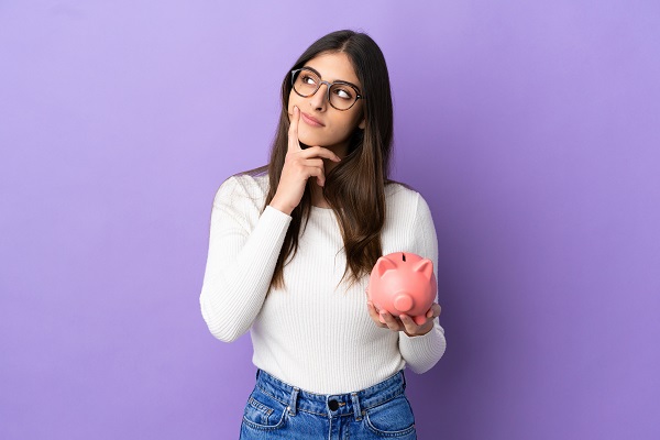 Young,Caucasian,Woman,Holding,A,Piggybank,Isolated,On,Purple,Background