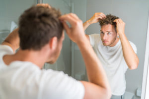 man checking his hair in the bathroom mirror