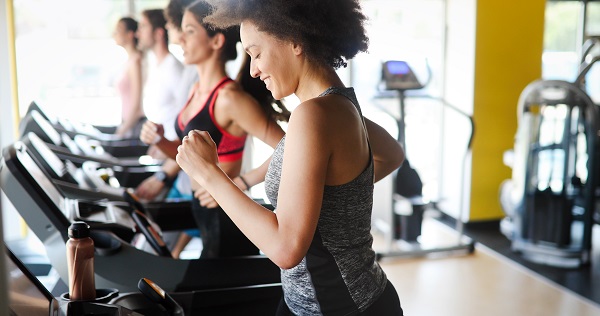 Group of fit people exercising in a gym cardio training and running