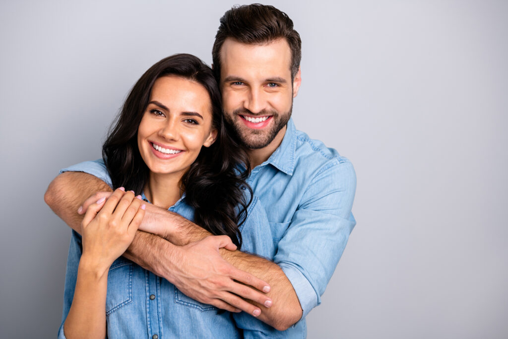 Portrait of cute adorable romantic fellows tender bonding best friends real soulmates enjoying each other placing arms around chest neck in blue denim shirts on grey background