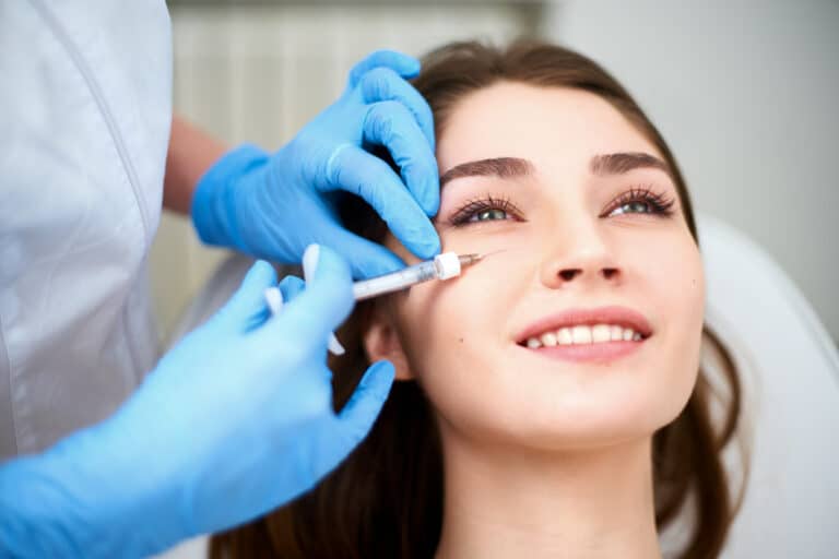 Doctor in medical gloves with syringe injects botulinum under eyes for rejuvenating wrinkle treatment. Filler injection for eye wrinkles smoothing. Plastic aesthetic facial surgery in beauty clinic